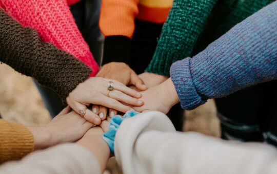 Team putting their hands in, illustrating Alibaba Cloud overhauling its global AI partner ecosystem.
