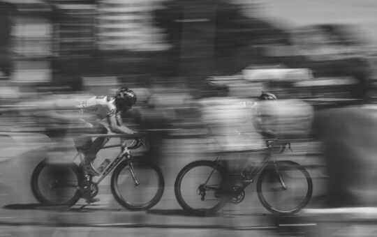 Two cyclists racing as the latest Qwen 2.5 AI model from Alibaba, Qwen 2.5-Max, outperforms competing artificial intelligence models such as DeepSeek V3 on several benchmarks.